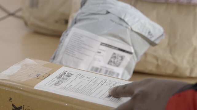 Gig worker scanning QR code of a parcel at warehouse, Closeup