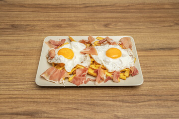 A plate with broken eggs, potatoes, and thinly sliced ​​ham, presented neatly before mixing everything together at mealtime