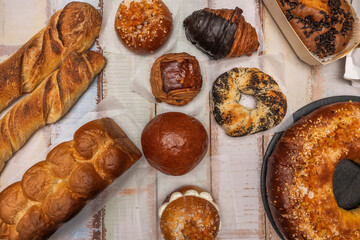 An evocative image featuring a traditional rosc&oacute;n (a ring-shaped cake) alongside rustic bread, oatmeal cookies, and shortbread, arranged on an antique, weathered wooden board.
