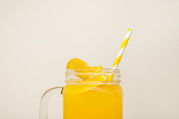 A tall, cylindrical glass pitcher, half-filled with a vibrant orange mango and passion fruit smoothie, boasting a creamy texture with no visible fruit pieces