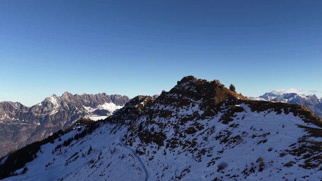 Churfirsten mountain range near Walensee Switzerland with drone slowly flying forward over snowy alpine ridge clear blue sky dramatic peaks travel nature and winter landscape.