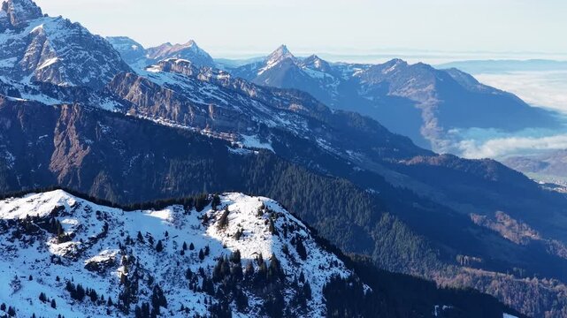 Churfirsten mountain range above Walensee near Flumserberg Flums Switzerland drone view, snow covered alpine peaks, deep valleys, forest slopes and winter landscape.
