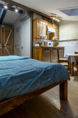 Rustic attic kitchenette with wooden cabinets and blue bedding