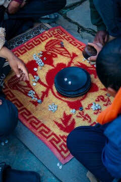 View of people playing a game with coins and bowls on a patterned mat, a moment of shared activity and cultural exchange, Himalaya, Nepal.