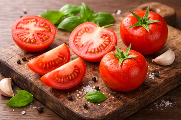 Fresh tomatoes and basil on a wooden cutting board with garlic and spices