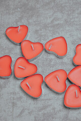 Fototapeta premium red heart-shaped candles arranged together on neutral background. Love, romance, Valentine’s Day, wedding decor, relationship, celebration and romantic lifestyle concept.