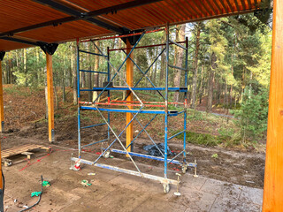 Scaffolding set up under a wooden structure in a forest area during daylight
