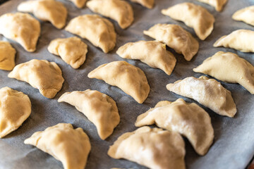 Fototapeta premium Dumplings are arranged on a baking tray ready for cooking in a kitchen