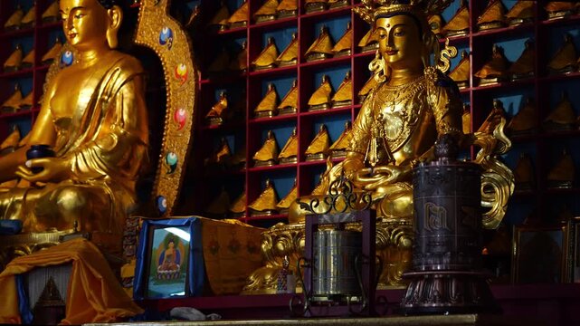 Golden Buddhist Statues and Spinning Prayer Wheel Inside Mongolian Temple
