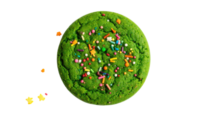 Overhead shot of a vividly green, round cookie with colorful sprinkles on a black background