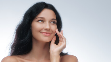 Fototapeta premium Smiling Woman With Glowing Skin Touching Face in Skincare Promo Shot