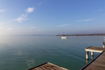 Fototapeta premium Sailing boat on calm water in Hungary near a wooden pier on a clear day in the afternoon