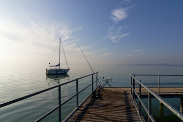 Sailboat moored at Balaton lake with fishing gear on the pier during early morning light