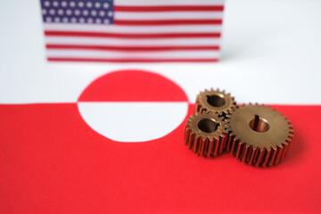 Metaphorical look at the relationship between America and Greenland. United States and Greenland relations concept with metal gears and blurred flags.