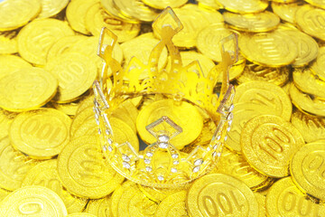 Gold crown on many golden coins background. Money and power concept.