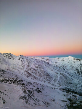 Aerial view of snow-capped mountains kissed by the pastel hues of dawn, where shadows dance across the pristine landscape, Les Belleville, Auvergne-Rhone-Alpes, France.