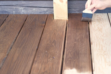 Brown oil for protection of wood by staining. Painting a larch for protecting and pests. Woodworker...