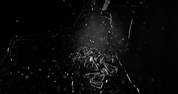 Front view of glass shattered by a bullet in super slow motion (1000fps). Gunshot impact creates cracks, flying shards and dust isolated on black background. Perfect VFX overlay element.