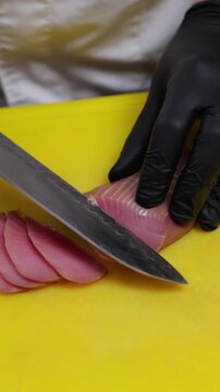 Professional chef skillfully slicing fresh, raw tuna