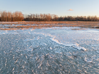 Aerial panoramic view of frozen pancake ice on the Baltic Sea coast in Estonia during a golden sunset winter evening