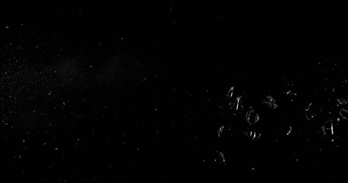 Super slow motion bullet impact shattering glass filmed at 1000fps. Side view of gunshot breaking window with flying shards and dust isolated on black background. Perfect VFX overlay element.