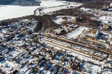 Breathtaking drone view of a snowy winter village, showcasing cozy homes, a long strip of garages, and a tranquil icy landscape beyond