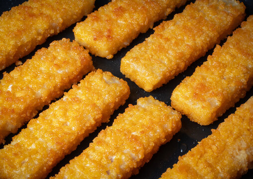 Crispy fish sticks frying in a pan close-up