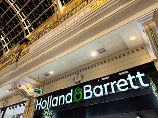 Naklejka premium Holland Barrett storefront in ornate Manchester shopping arcade interior at night