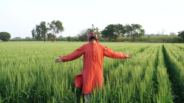 happy indian farmer standing at agricultural field