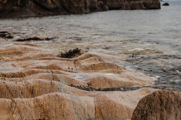 A rocky beach with eroded limestone, waves lapping against the rocks, Ireland © Olha K