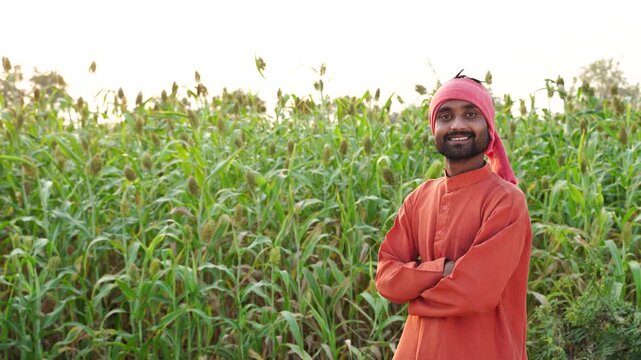 young indian farmer standing at green agricultural field