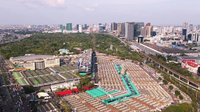 Aerial footage of Chatuchak Weekend Market, one of largest outdoor markets in the world, with modern Bangkok skyline in the background