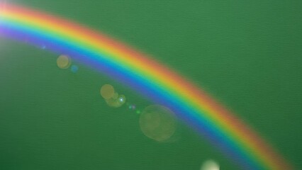 Rainbow arc across green background for Saint Patrick day. Vibrant color spectrum light flare on textured surface for Irish celebration.