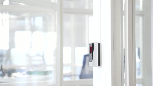 Close up of a businessman opening a glass office door holding a doorknob in modern business center. A man, employee in a shirt opens the door and enters the bright office to the workplace. Front view