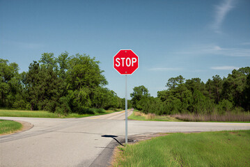 Red Stop Sign at Rural Gravel Road Intersection. Countryside Path, Blue Sky, Road Safety, Travel & Navigation.