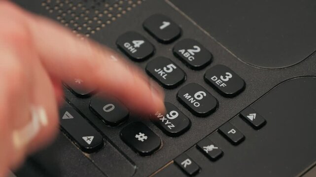 Fingers nervously dial 911 on a landline home phone. High quality 4k footage