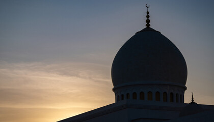 Silhouette of a mosque dome against a sunset sky.