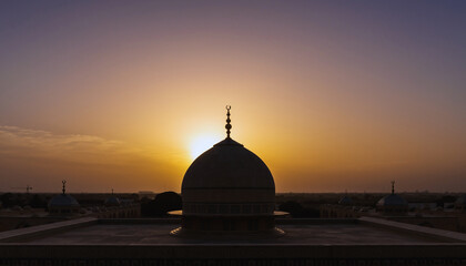 Naklejka premium Silhouette of a mosque dome against a vibrant sunset sky 1.
