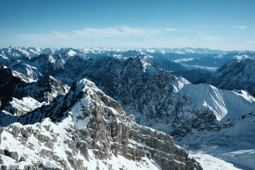 Panoramic view of rugged snow-covered mountain ridges and alpine layers from Zugspitze, Germany.
