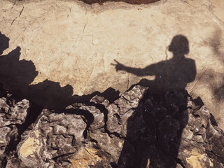 Shadow of a woman cast on stone ground beside a waterfall, creating a quiet and contemplative...