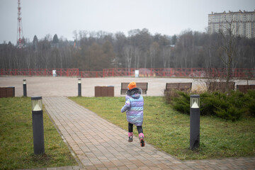Child running through an empty park. Child alone in the afternoon on the street.