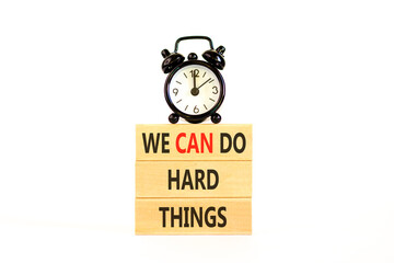 Naklejka premium Support, help we can do hard things symbol. Concept words We can do hard things on beautiful wooden blocks. Beautiful white background. Alarm clock. Business we can do hard things concept. Copy space.