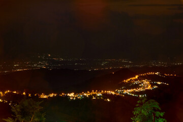 High angle view of illuminated city on mountain peak against sky at night