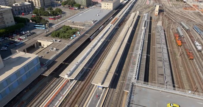 High-angle aerial view of a large railway station. Parallel tracks, platforms, and trains create a geometric pattern, highlighting urban transport infrastructure. It is Messina Centrale, Sicily, Italy
