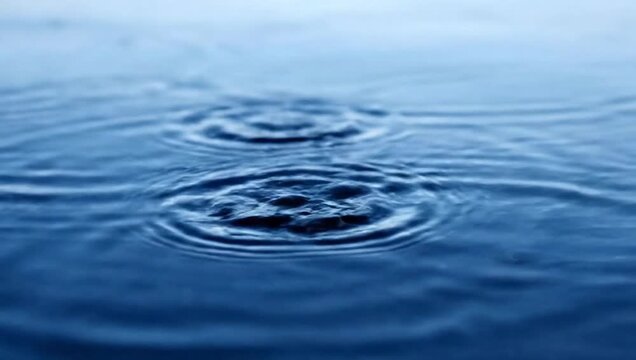 Close up of water ripples and drops falling into the water creating concentric circles.