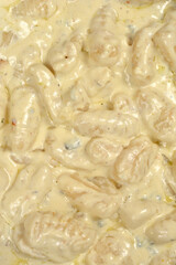 A close up top view shows a delicious portion of homemade gnocchi covered in a thick and smooth gorgonzola cheese sauce with visible spices