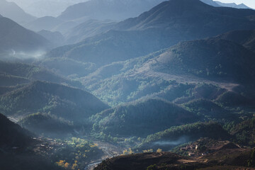 Mountain landscape in the Atlas Mountains of Morocco, layered hills with forests and valleys in soft morning light, rural scenery, natural background, panoramic view.