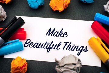 Paper with words Make Beautiful Things, colour pens and crumpled paper balls on gray background.