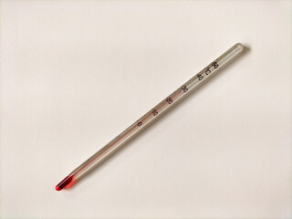 Glass medical thermometer with red liquid indicator on a white background.