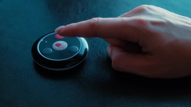 Finger pressing a wireless call button on restaurant table in dark moody light. Concept of calling waiter, customer service, hospitality and smart dining technology